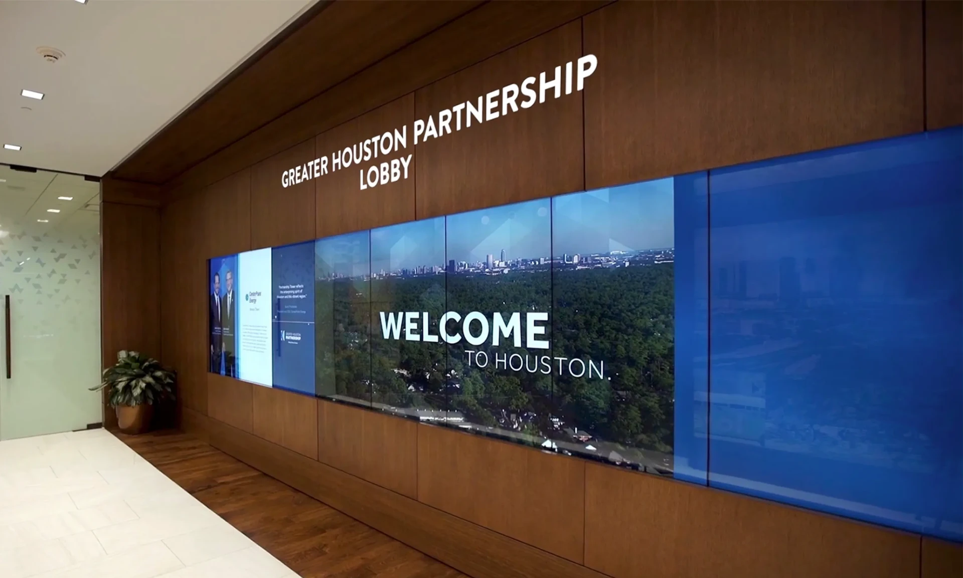 Modern corporate office with multiple digital signage screens showing KPIs and company news