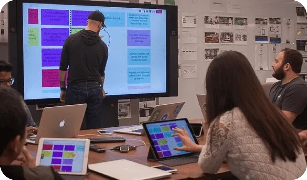 Team workshop with people collaborating around a large interactive display in a fitness studio