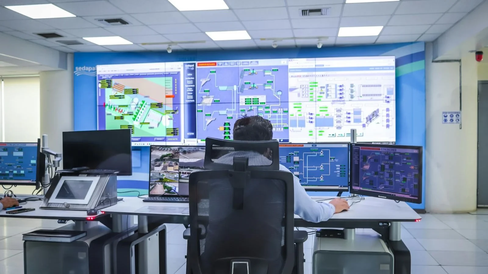 Operator working in front of a wall of dashboards in a control room